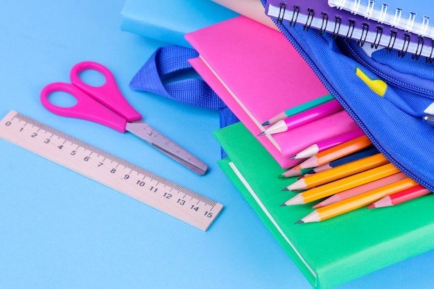 school supplies falling out of a  school backpack on a  blue background