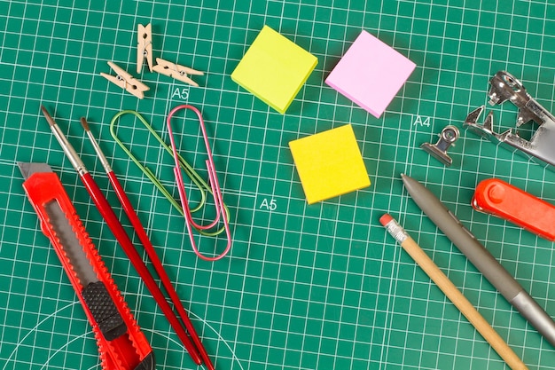 School supplies on a green cutting mat in a top view