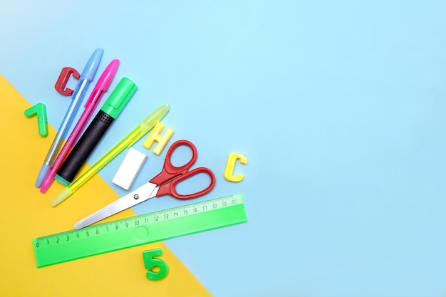 School supplies ruler pens eraser letters scissors marker on a yellowblue background with copy space