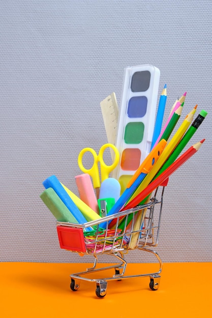 School supplies and stationery in a shopping basket gray backgroundPreparing child for school year