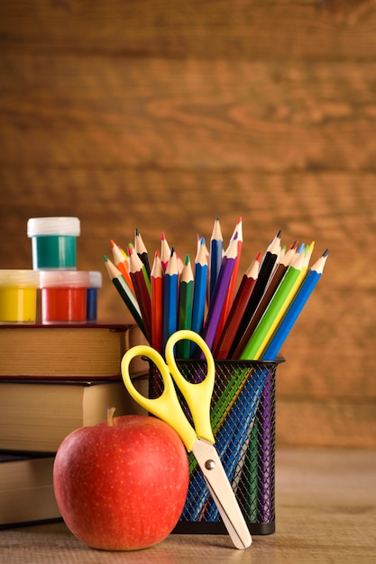 School supplies on a warm, beautiful wooden wall. Colored children's pencils in a locker black holder for stationery.