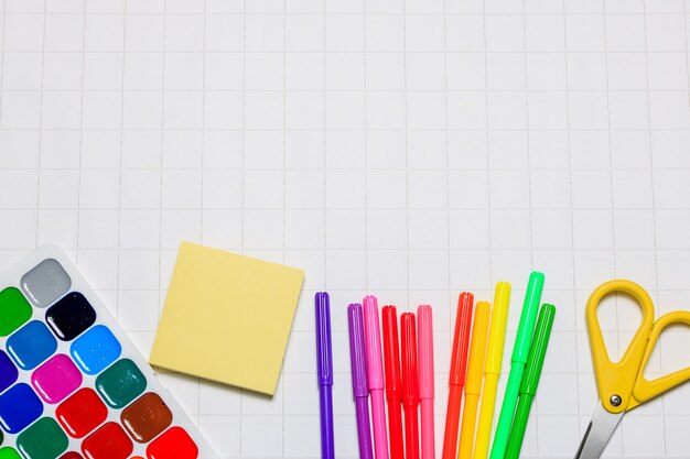 School supplies on a white checkered paper background Back to school New academic year begin