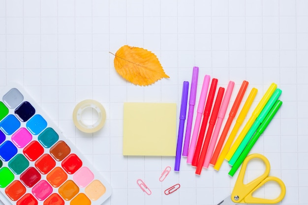 School supplies on a white checkered paper background Back to school New academic year begin