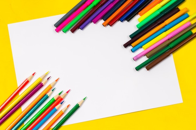 School supplies and white sheet on a bright yellow background ready for your design