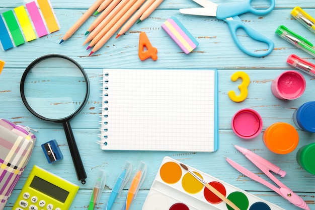 School supplies with notebook on blue wooden background. Back to school. Flat lay. Top view