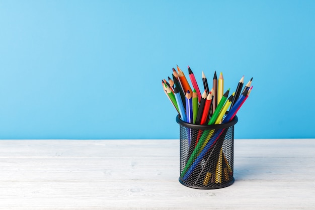 School supplies on wooden desk against blue background front view