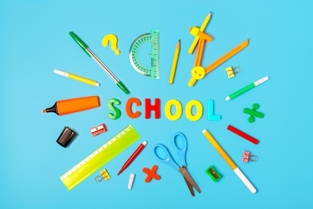 School supplies and the word school from multicolored letters on a blue background Back to school concept school learning and education concept Stationery store concept flat lay top view