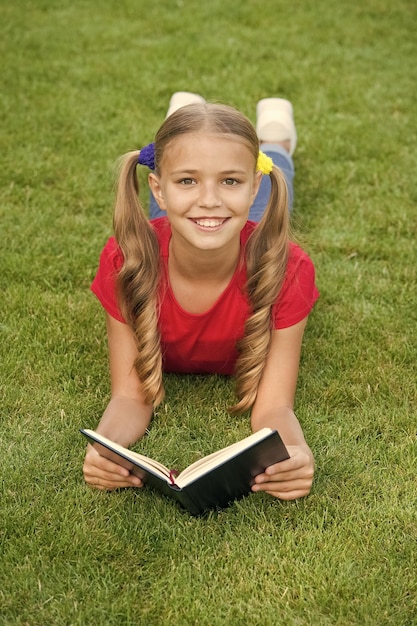 School time Interesting stories for kids Study with pleasure Time for great stories Little child reading book outdoors Schoolgirl read stories while relaxing green lawn Cute pupil enjoy reading