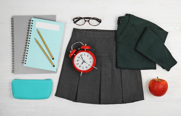 Photo school uniform for girl and stationery on white wooden background top view