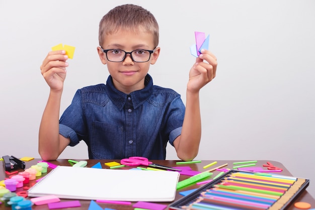 Schoolboy in a blue shirt sitting at the table. Boy with glasses. Concept back to school