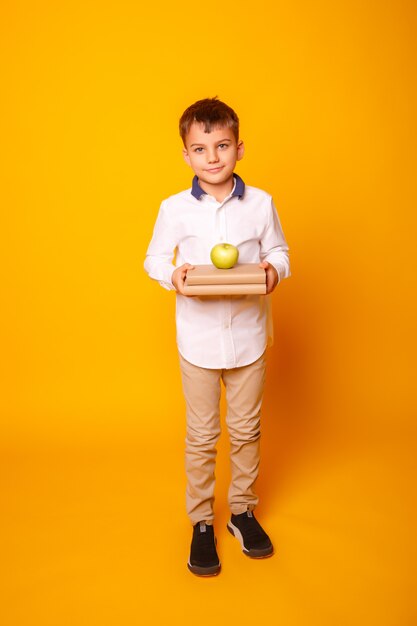 a schoolboy boy holds a book with an Apple