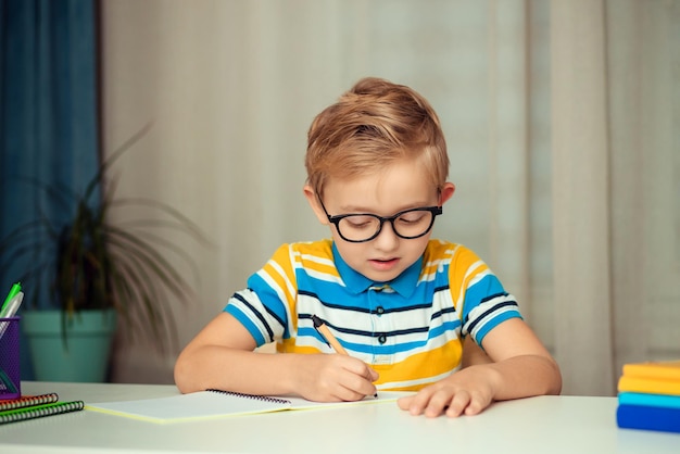 The schoolboy does his homework sitting at the table at home