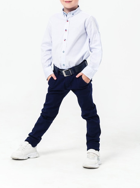 Photo schoolboy in a school uniform on a white background the boy demonstrates a shirt trousers a belt and sneakers vertical photo