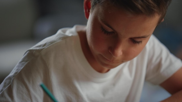 Schoolboy solving problems in notebook Thoughtful boy studying at home