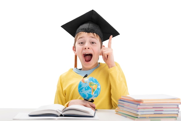 Schoolboy in student hat raised index finger up over white background Concept idea or insight in child Excellent student