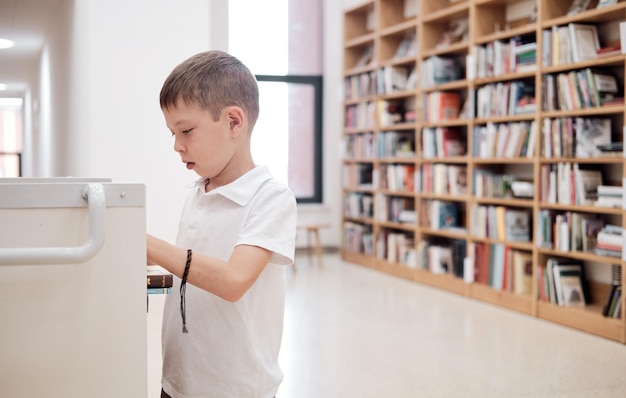 A schoolboy in a white Tshirt puts books in a cart in the library copy space Reading outside of school