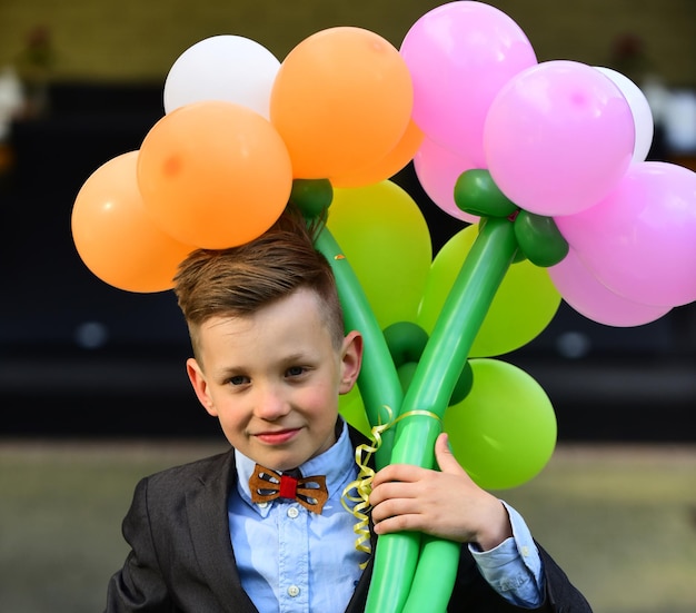 Schoolboy with bouquet of flowers and balloons goes to school on september  new academic year