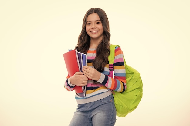 Schoolchild teenage student girl with school bag backpack hold book on white isolated studio background Children school and education concept Happy girl face positive and smiling emotions