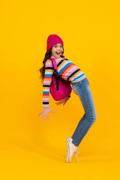 Schoolgirl child student with backpack warn hat isolated yellow background Learning and knowledge