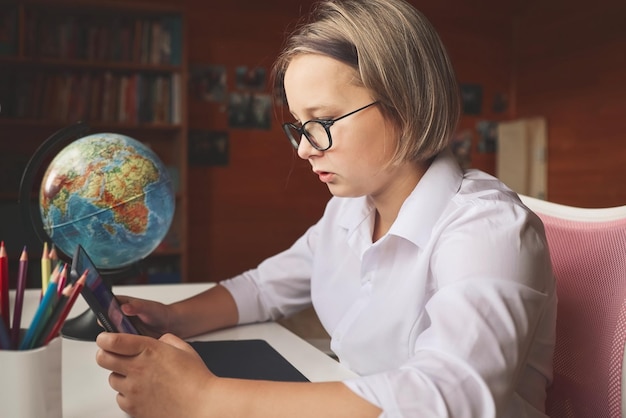 Schoolgirl engaged in homeschooling watching online learning lecture on laptop at home Kid attending remote virtual school class listening to teacher Remote learning at home with technology