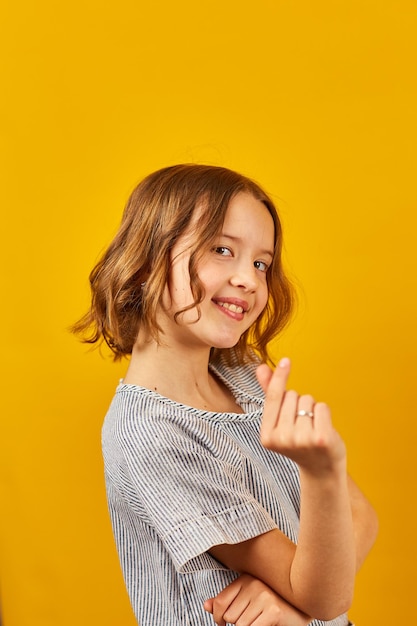 Schoolgirl Making Heart Shape With Hands Against a Vibrant Yellow Background