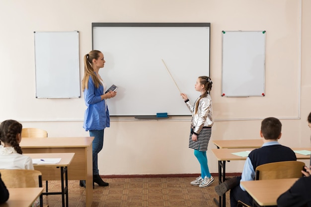 Schoolgirl near the board with a pointer