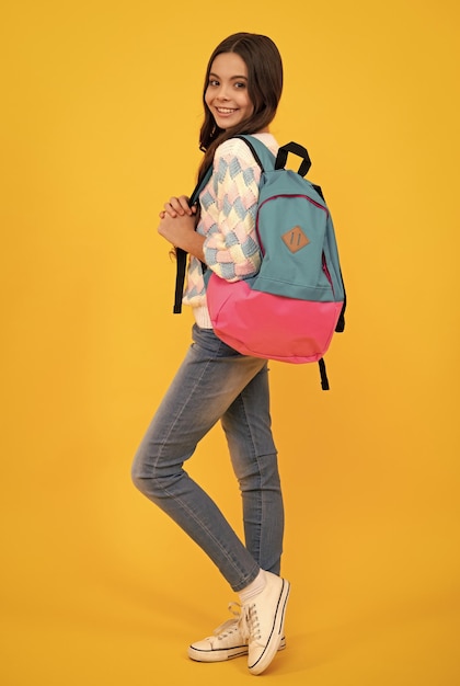 Schoolgirl in school uniform with school bag Schoolchild teen student hold backpack on yellow isolated background