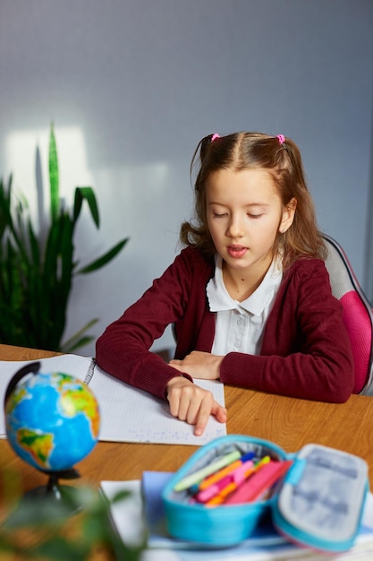 Schoolgirl sit at desk doing homework reading homeschooling