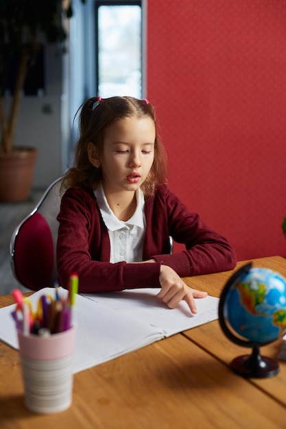 Schoolgirl sit at desk doing homework reading homeschooling