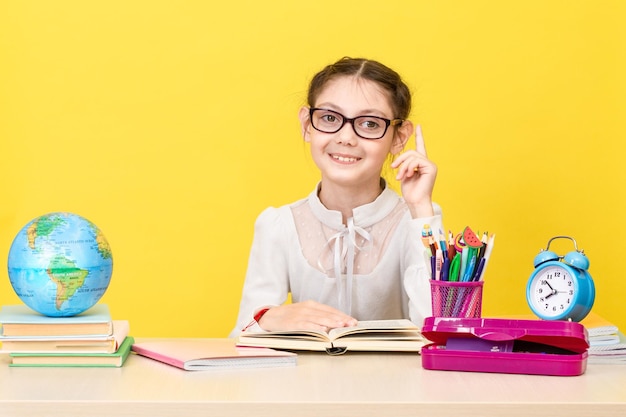 The schoolgirl sits at the desk and thinks about the decision of the task