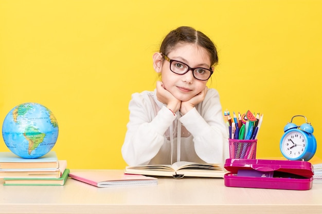 The schoolgirl sits at the desk and thinks about the decision of the task