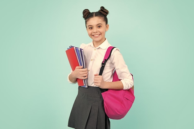 Schoolgirl teenage student girl hold book on blue isolated studio background School and education concept Back to school Happy teenager positive and smiling emotions of teen girl