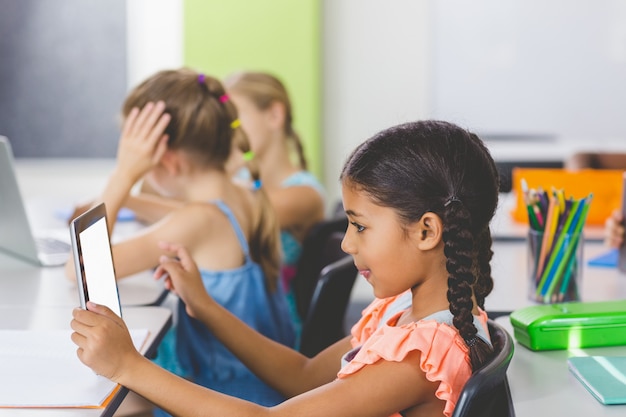 Schoolgirl using digital tablet in classroom