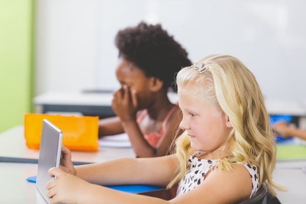 Schoolgirl using digital tablet in classroom