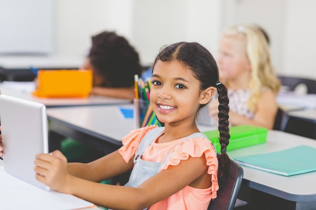 Schoolgirl using digital tablet in classroom