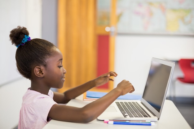 Schoolgirl using laptop in classroom