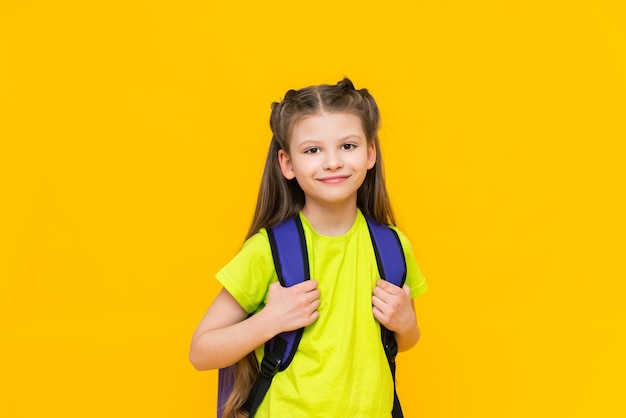 A schoolgirl with a backpack A little girl with a satchel on her back Teaching children Supplementary education of the child Educational preparatory courses for school Yellow isolated background