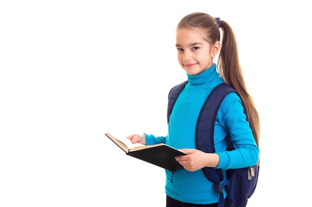 Schoolgirl with book in hands looking in camera at white isolated background.