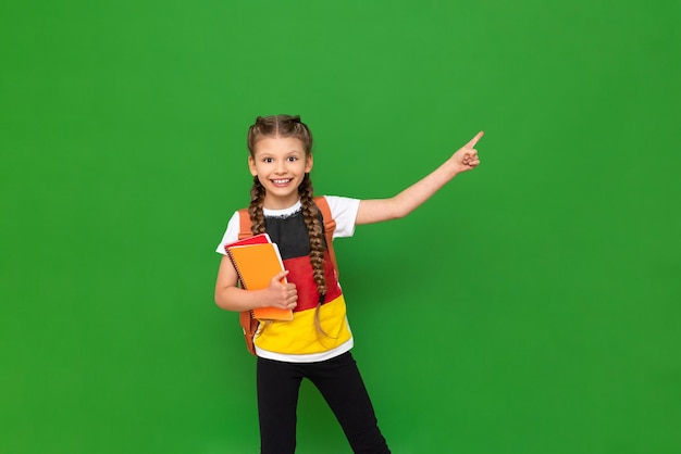 A schoolgirl with a German flag on her Tshirt points to the side at an advertisement on a green isolated background Education abroad