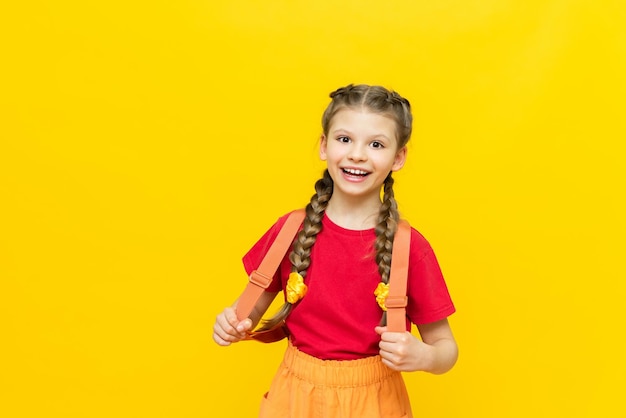 A schoolgirl with a satchel is getting ready to go to school Children's education Preparatory courses for schoolchildren Additional classes for successful exams Yellow isolated background