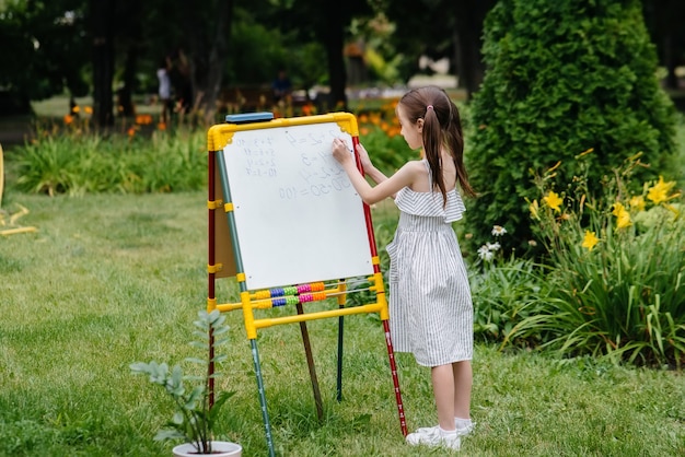 A schoolgirl writes lessons on a blackboard and is engaged in outdoor training