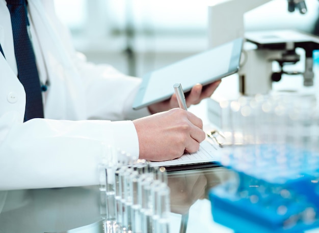 Science lab technician with a digital tablet making notes on the clipboard