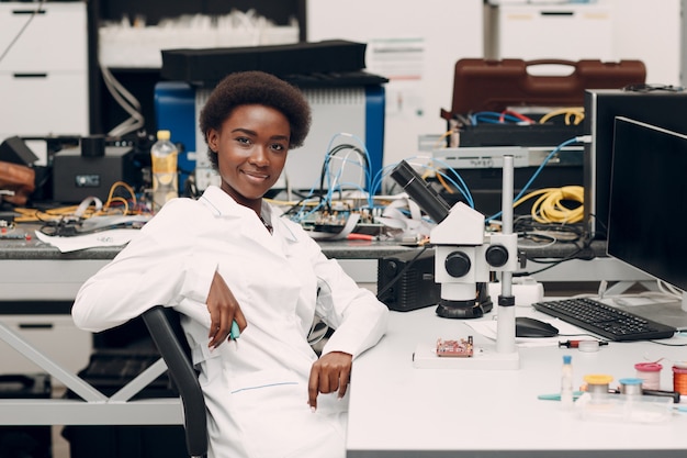 Scientist african american woman engineer in laboratory with microscope