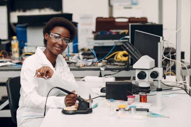 Scientist african american woman working in laboratory with soldering iron research and development of electronic devices by color black woman