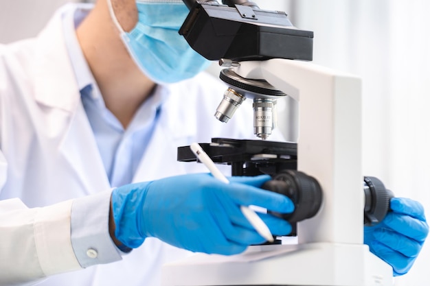 Scientist analyzing microscope slide at laboratory Young woman technician is examining a histological sample a biopsy in the laboratory of cancer research