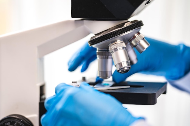 Scientist analyzing microscope slide at laboratory Young woman technician is examining a histological sample a biopsy in the laboratory of cancer research