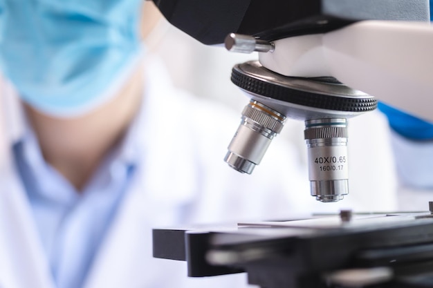 Scientist analyzing microscope slide at laboratory Young woman technician is examining a histological sample a biopsy in the laboratory of cancer research