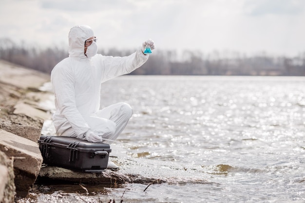 Scientist or biologist wearing protective uniforms examining the liquid contents of a test tube xA