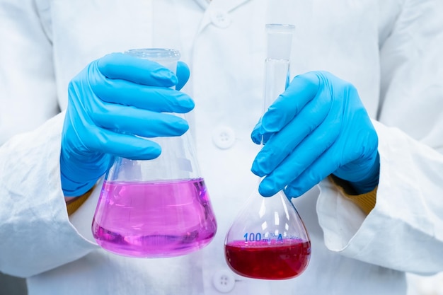 Scientist doing experiments with bright solutions in the flasks at the chemical laboratory researche