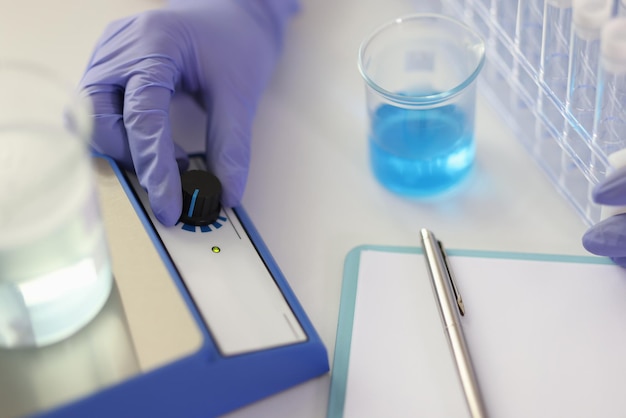 Scientist examines clear blue liquid samples in laboratory assistant in protective gloves makes